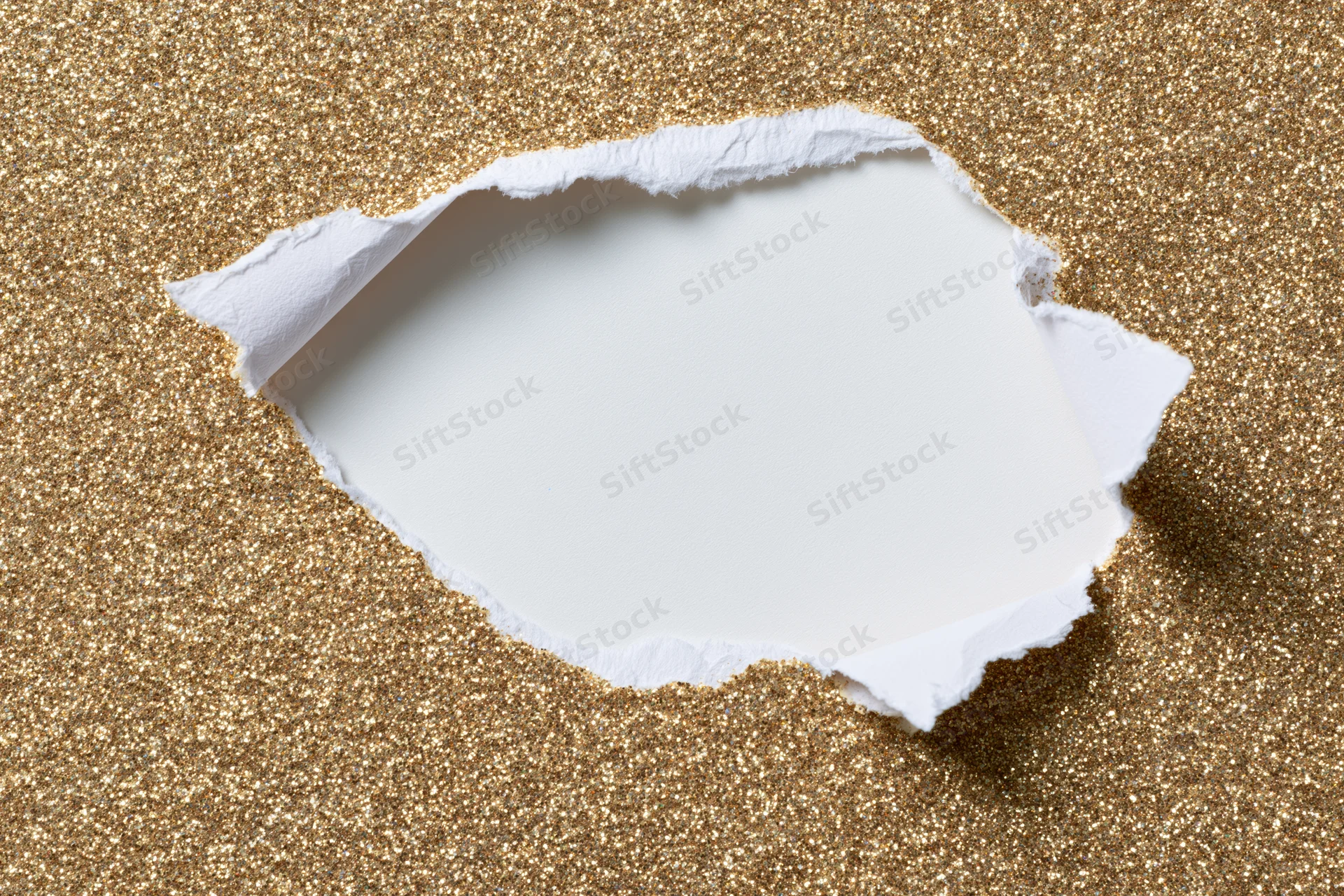 Torn hole in gold glitter paper revealing white space