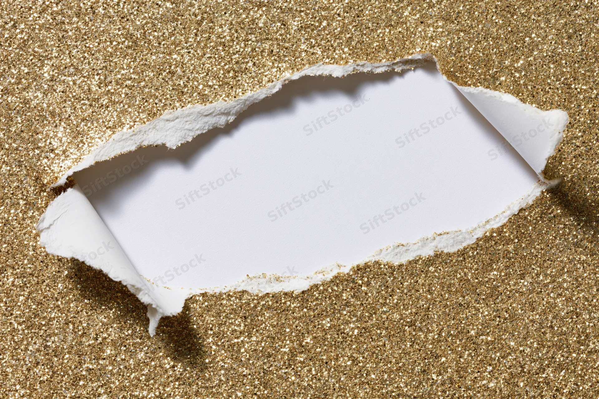 Torn hole in gold glitter paper revealing white space