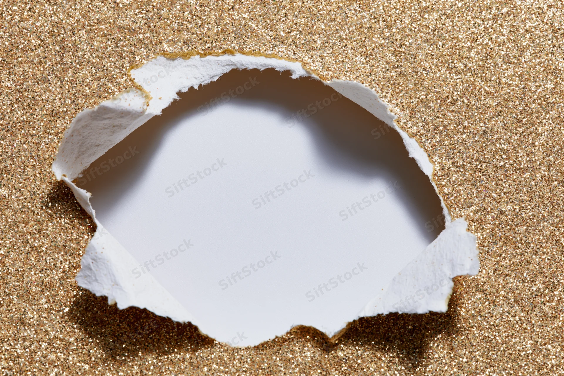Torn hole in gold glitter paper revealing white space