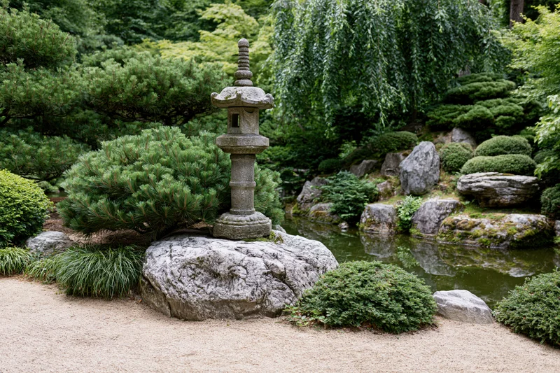 Stone lantern on a rock in a traditional japanese garden with gravel, water, and greenery