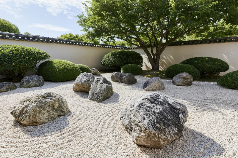 Traditional japanese zen garden with raked gravel and arranged rocks surrounded by trimmed shrubs and a tiled wall