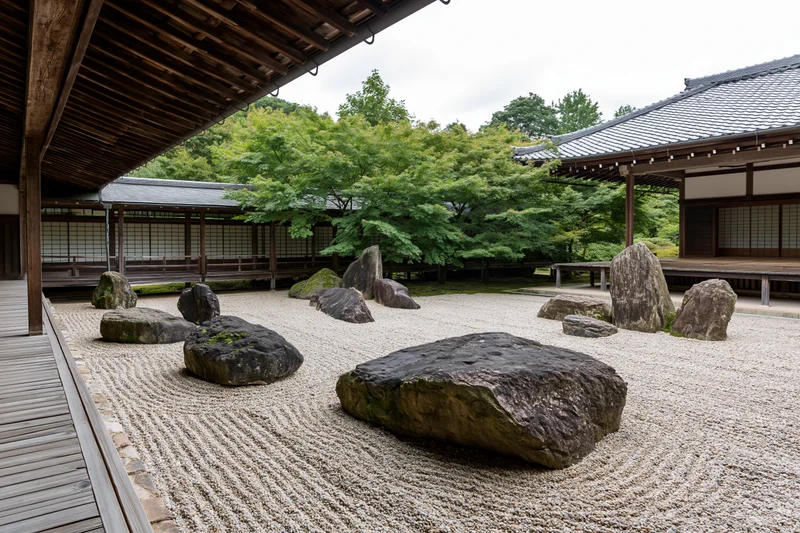 Traditional japanese zen garden with raked gravel and arranged rocks surrounded by wooden buildings and greenery