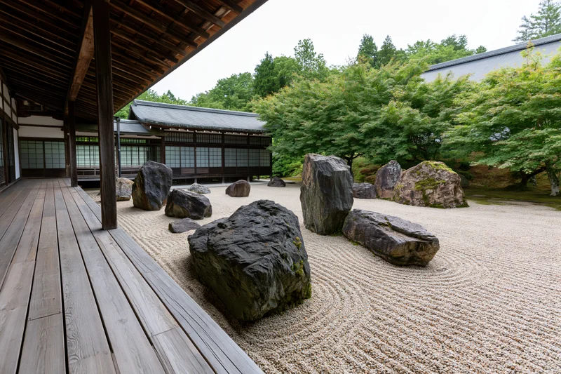 Traditional japanese zen garden with raked gravel and large rocks arranged in a courtyard beside a wooden veranda