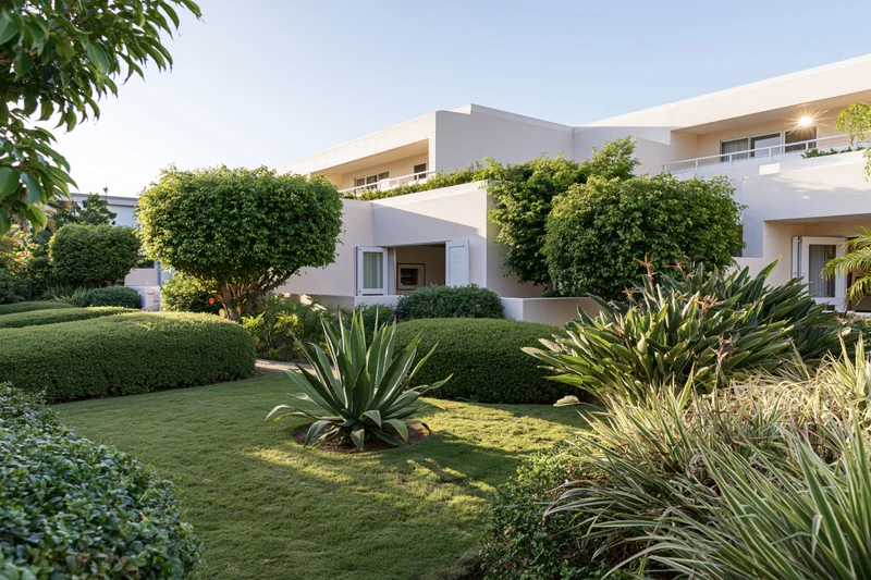 Tropical resort garden courtyard with manicured lawn and lush greenery surrounding a modern white building