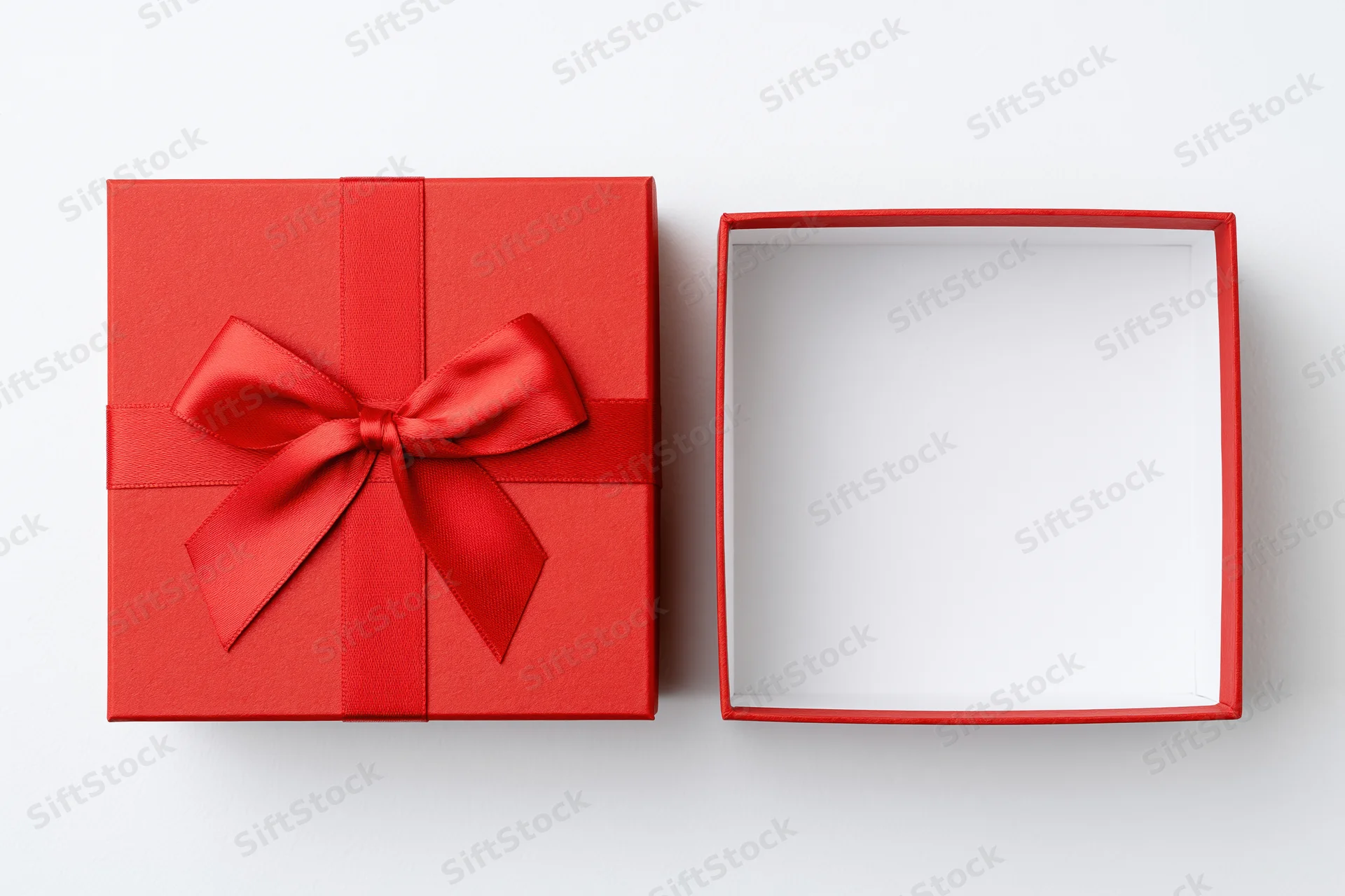 Red gift box with ribbon and open lid on white surface