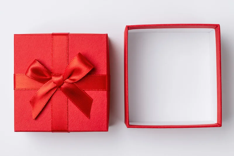 Red gift box with ribbon and open lid on white surface