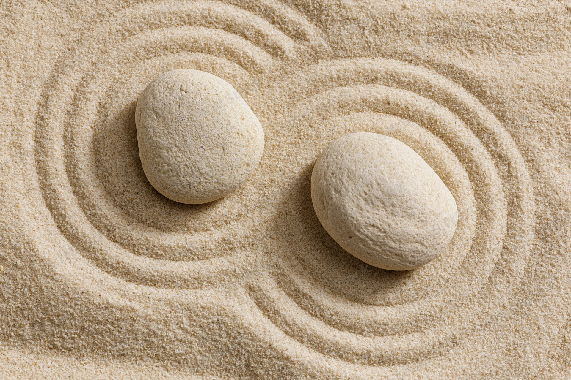 Two smooth stones resting on raked sand in a zen garden