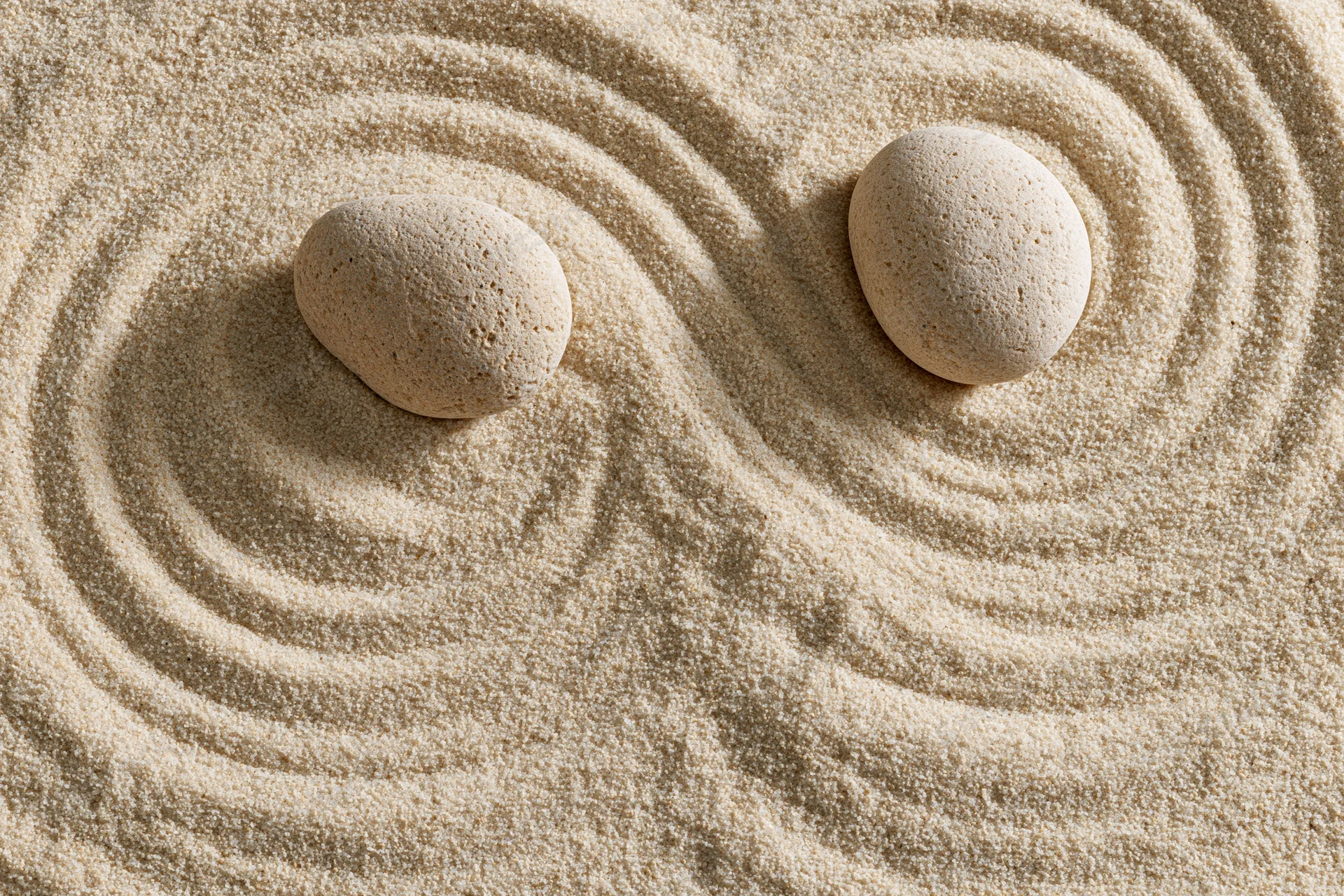 Two smooth stones resting on raked sand in a zen garden
