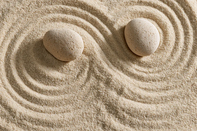 Two smooth stones resting on raked sand in a zen garden