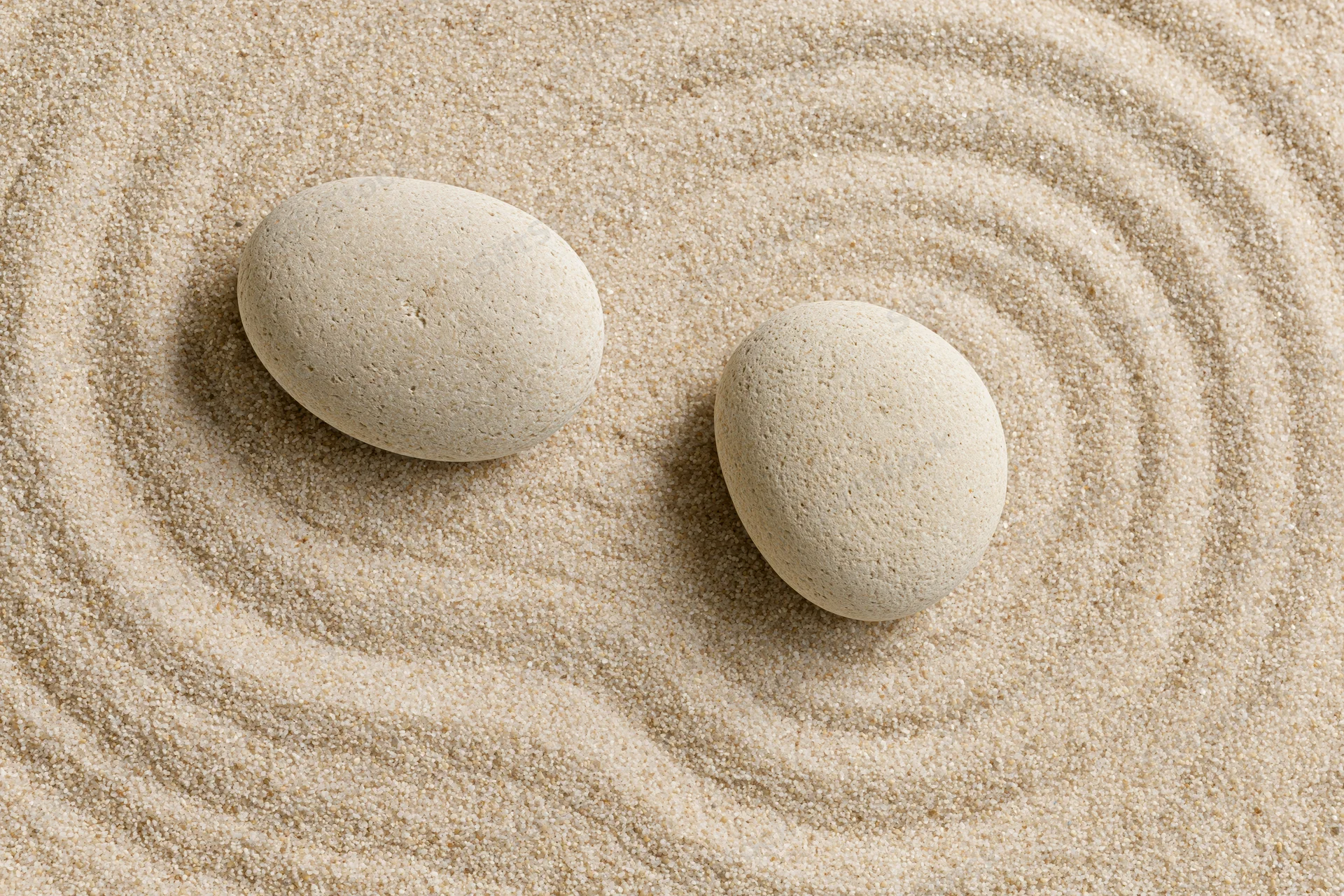 Two smooth stones resting on raked sand in a zen garden
