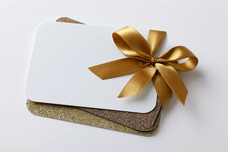 Stacked gift cards with gold ribbon bow on white background