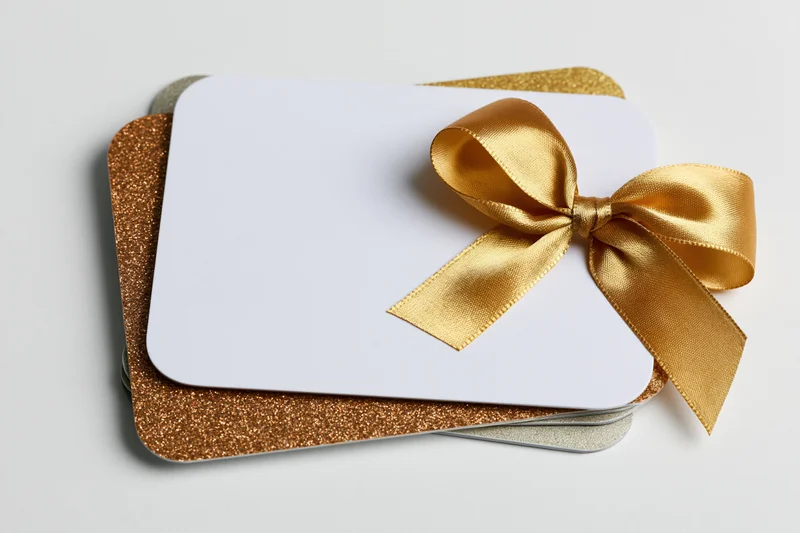 Stacked gift cards with gold ribbon bow on white background
