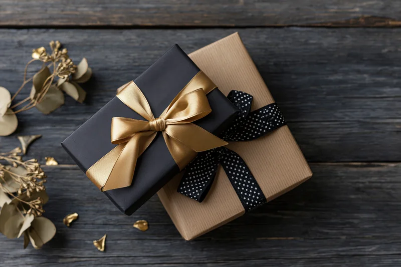 Two wrapped gift boxes with ribbons and bows on a dark weathered wooden surface