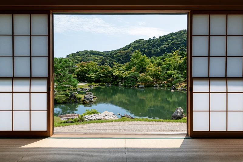 View through open shoji doors onto a tranquil japanese garden with pond and forested hill