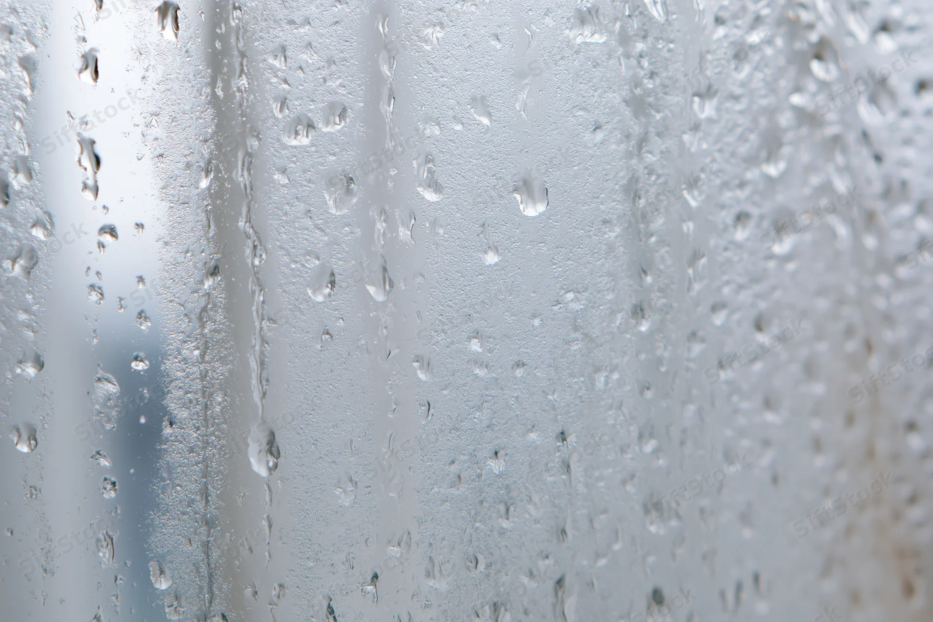 Water droplets condensed on a glass window pane in macro closeup