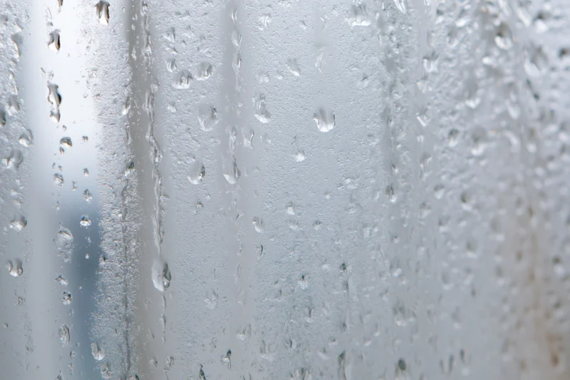 Water droplets condensed on a glass window pane in macro closeup