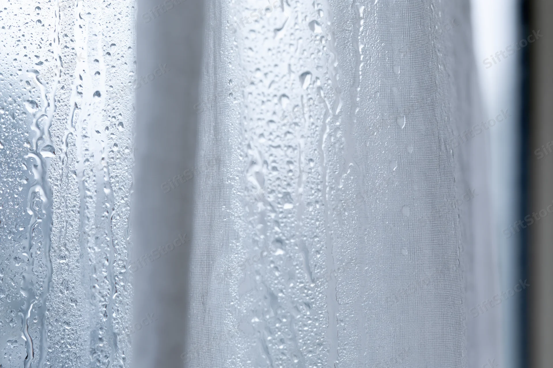 Water droplets condensed on a glass window pane in closeup view