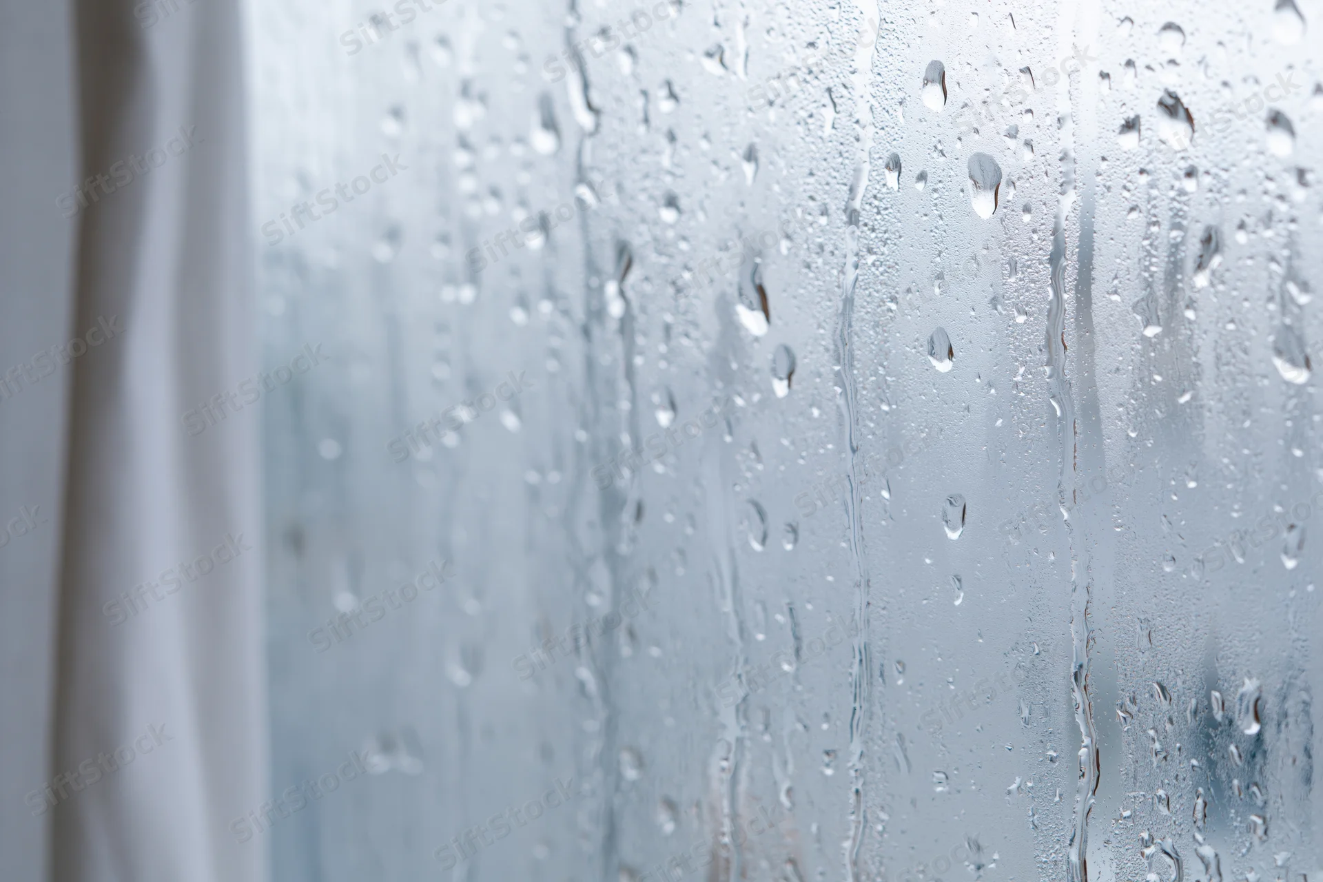 Water droplets condensed on a glass window pane in closeup view