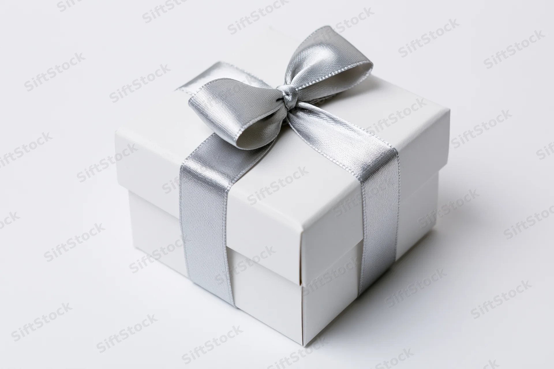 White gift box wrapped with silver satin ribbon on plain white background