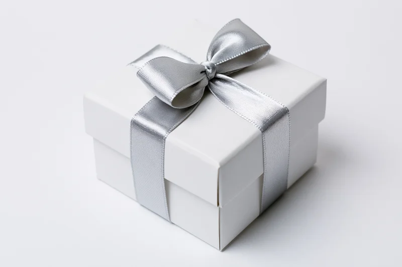 White gift box wrapped with silver satin ribbon on plain white background