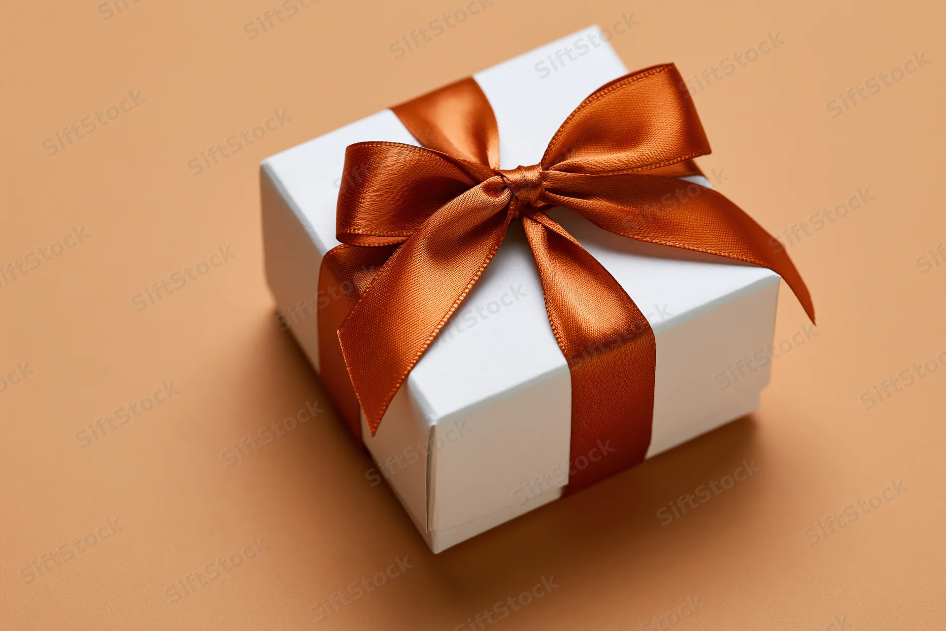 White gift box tied with a glossy burnt-orange satin ribbon on a solid background