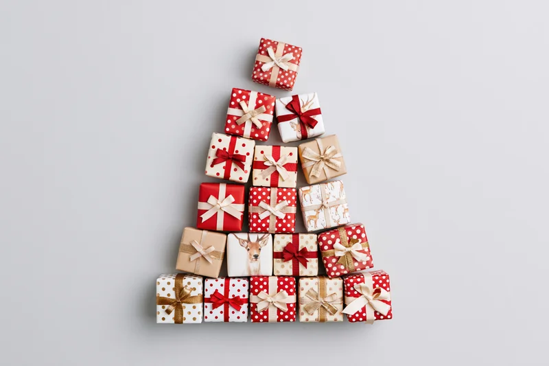Wrapped gift boxes arranged in triangular tree shape on light gray surface