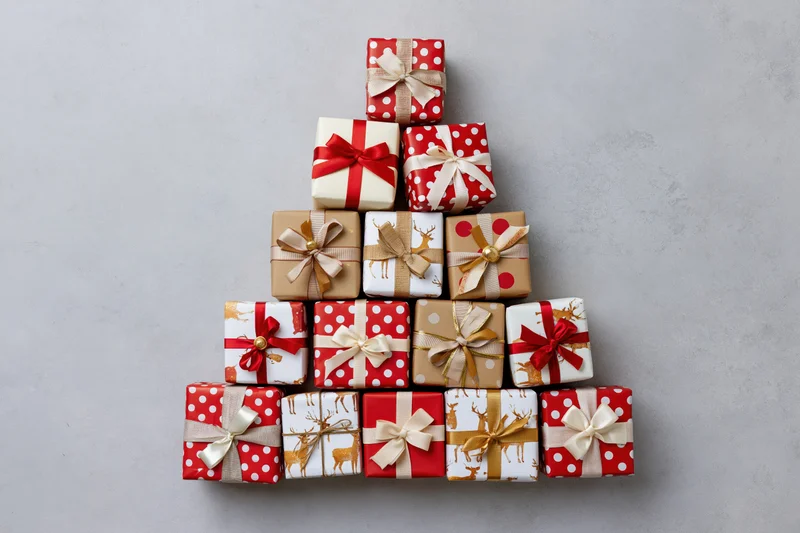 Wrapped gift boxes arranged in triangular tree shape on gray surface