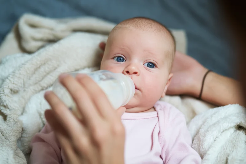 Baby being bottle fed while cradled in a soft blanket