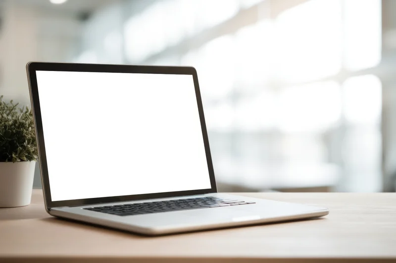 Silver laptop with blank screen on wooden desk in bright office workspace