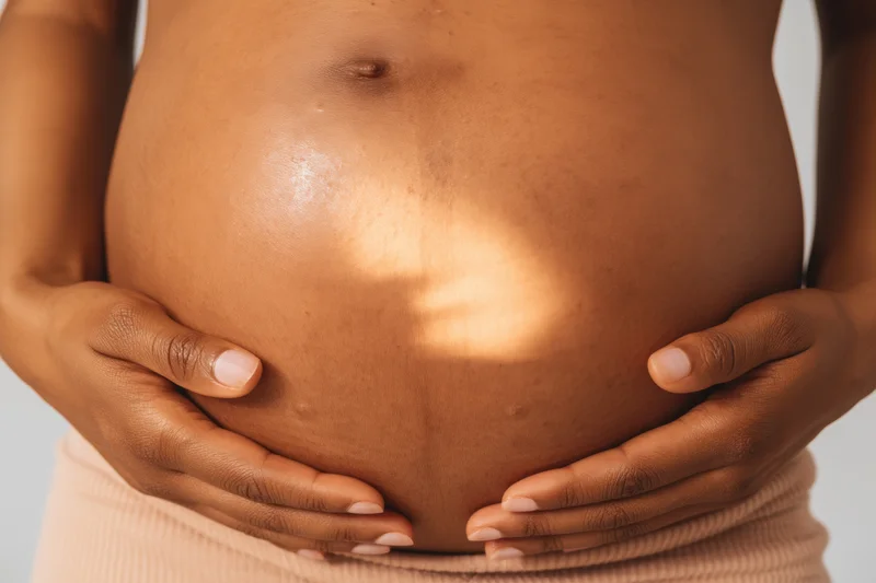 Pregnant woman's belly cradled by hands in soft light