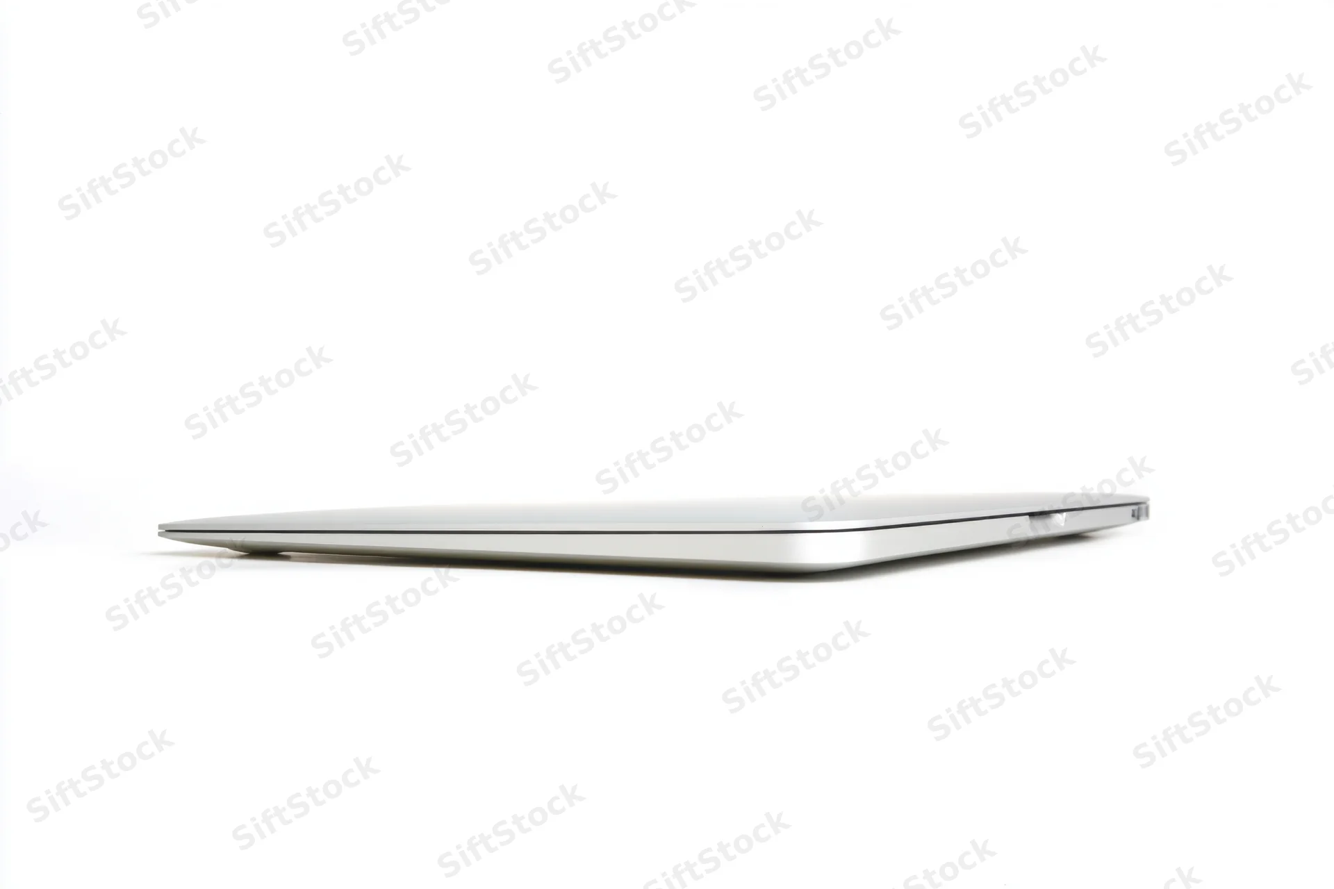 Closed silver laptop viewed from the back on a white surface