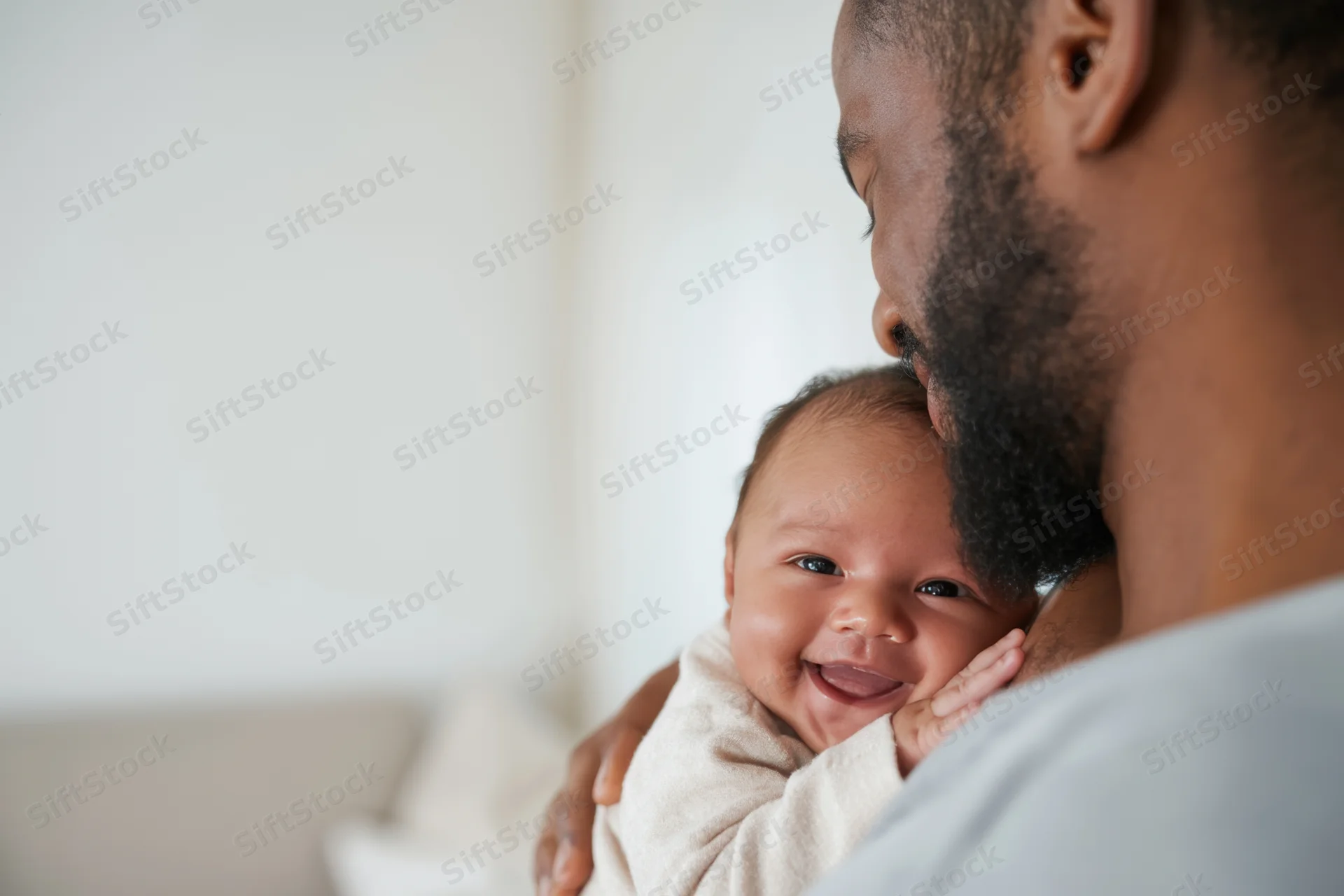 Father cradling smiling newborn baby in home setting