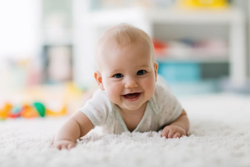 Baby crawling on white fluffy rug smiling happily indoors