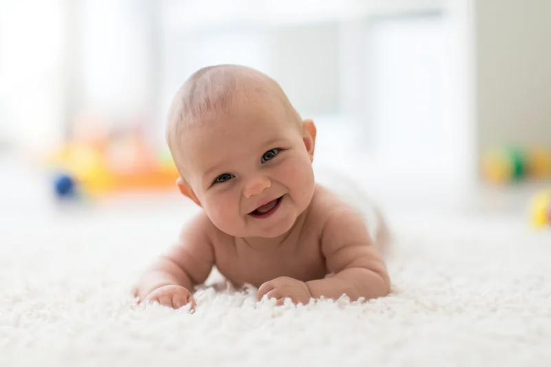 Baby lying on white fluffy rug smiling during tummy time in bright indoor setting