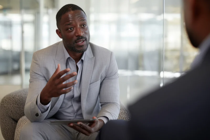 Man in gray suit gesturing with tablet during office meeting