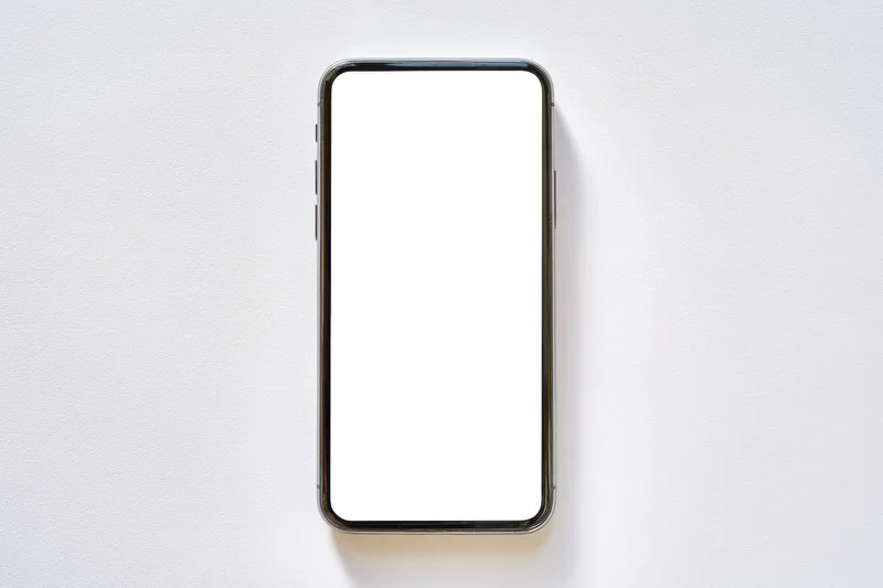 Modern smartphone with blank white screen lying flat on white surface