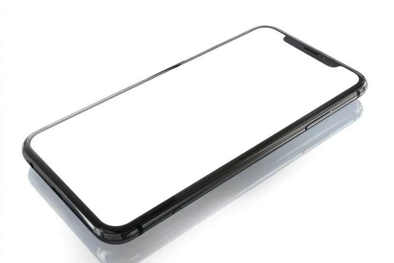 Modern smartphone with black frame and white screen lying on reflective surface