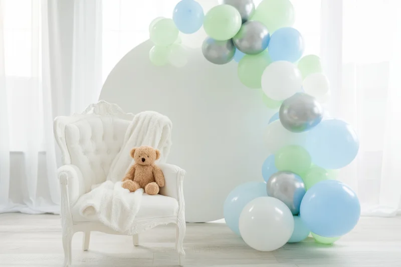Pastel balloon arch and teddy bear on white tufted chair in bright nursery setting