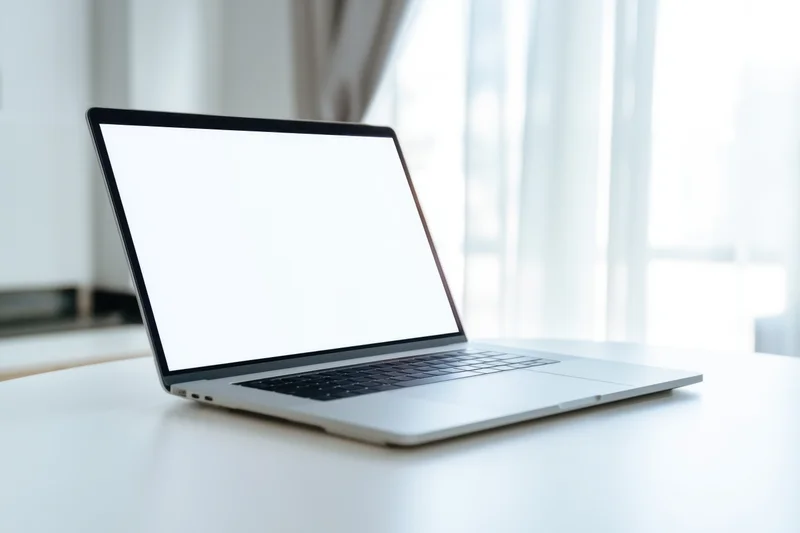 Sleek silver laptop with blank white screen on white desk near window