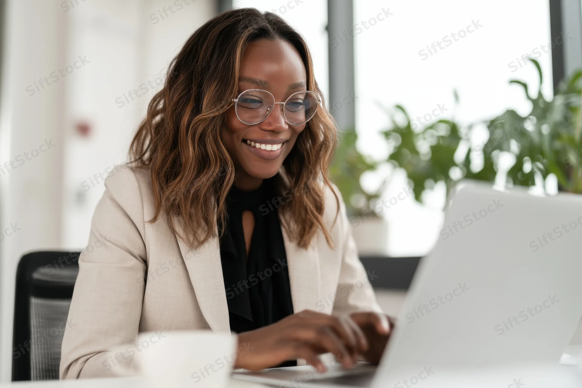 Smiling professional woman typing on laptop at office desk