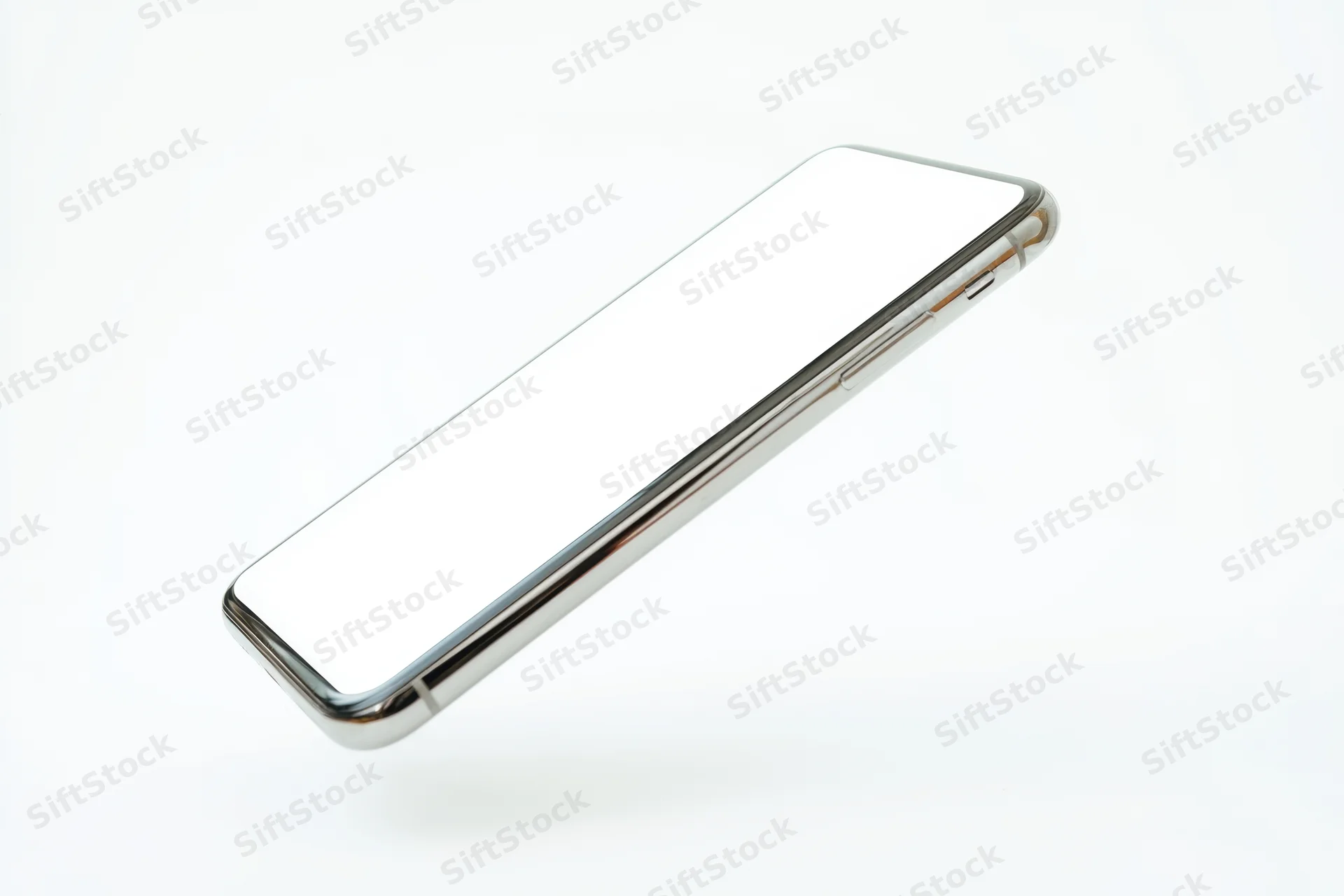 Tilted smartphone with blank white screen and metallic frame floating against white background