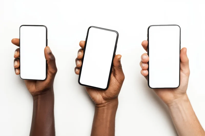 Three hands of different skin tones holding smartphones with blank white screens against a white background