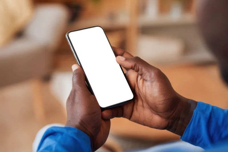 Man holding smartphone with blank white screen indoors