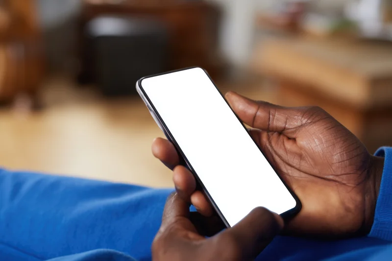 Man holding smartphone with blank white screen indoors
