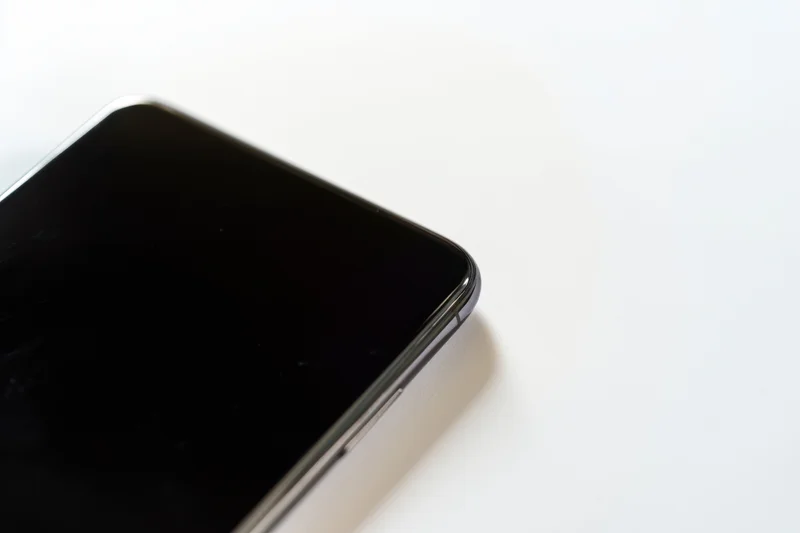 Close-up of a modern smartphone corner on a white surface with copyspace