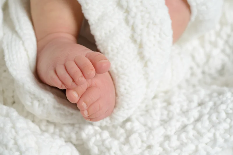 Curled baby feet resting on a white knitted blanket
