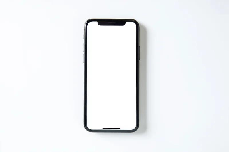 Black smartphone with white screen lying flat on white surface