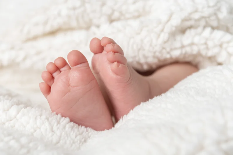Baby's tiny feet resting on a fluffy white blanket