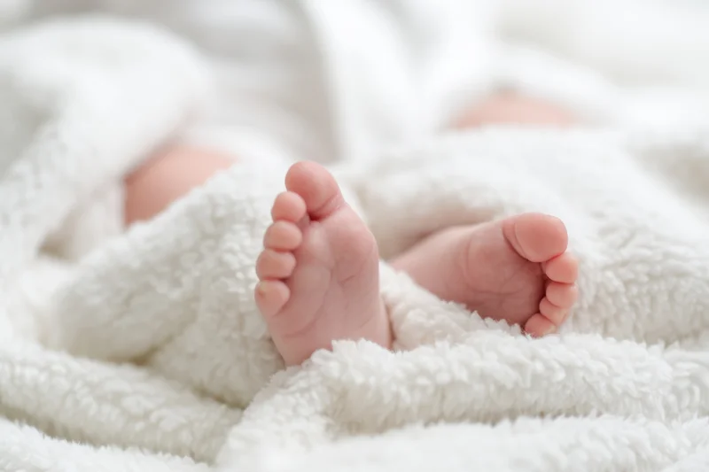 Close-up of a baby's tiny feet resting on a fluffy white blanket