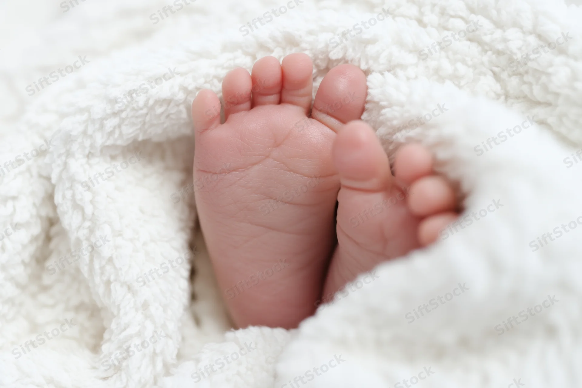 Baby's tiny feet resting on a fluffy white blanket